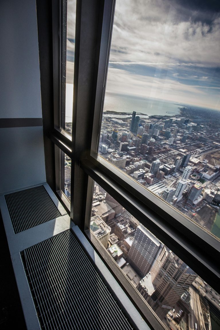 Stunning aerial view of Chicago cityscape through a skyscraper window with Lake Michigan in the background.